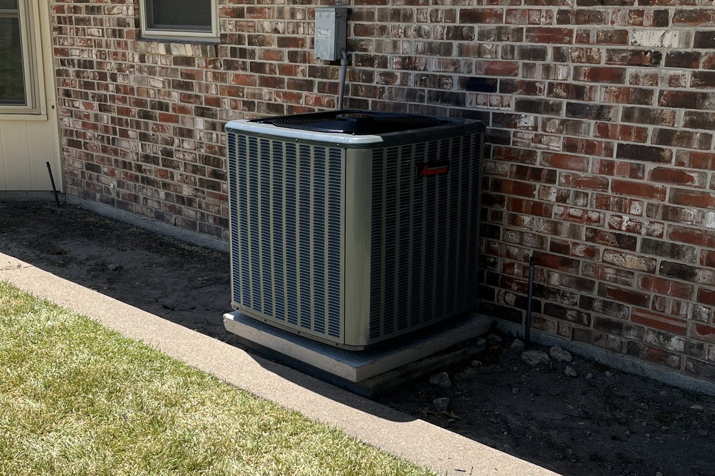 Newly installed Amana air conditioner outside a brick home