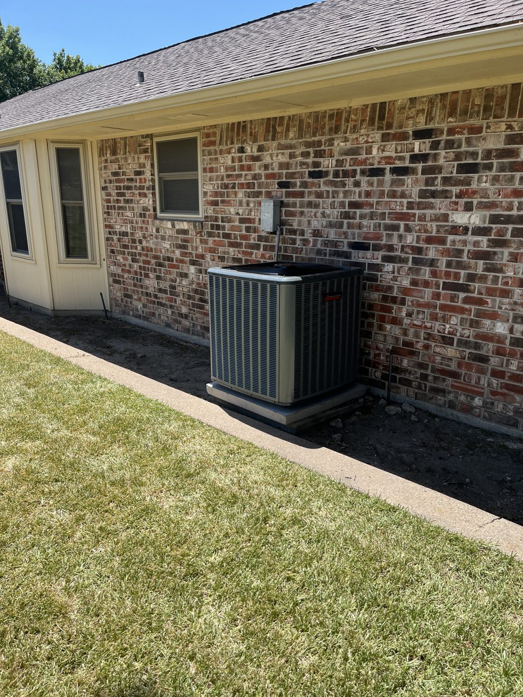 New Amana condenser installed beside a brick home